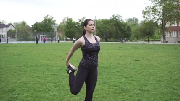 Tema esporte e saúde. Jovem mulher bonita fazendo aquecimento, aquecendo os músculos, esticando grama verde . — Vídeo de Stock