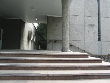 Ofis binasına giriş. Merdivenleri, merdivenleri ve sütunları olan beton bina. Hiç kimse. Gri beton kentsel grunge arka planı.