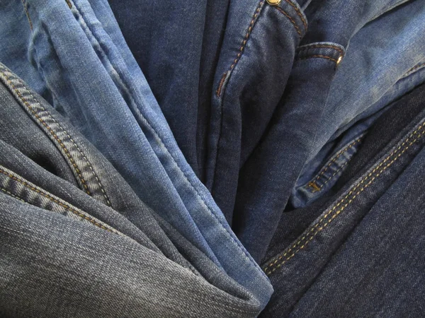 Pile of jeans background. Heap of old jeans. Stack of blue jeans. Blue grunge background. Casual style of clothes.