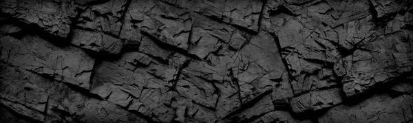Black and white background. Black rock texture. Grunge stone background. The texture of the mountains. Close-up. Grunge banner with volumetric rock texture.