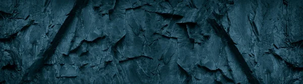 Dark blue green stone background. Grunge background. Banner with toned rock texture. The combination of teal color and rough mountain texture.