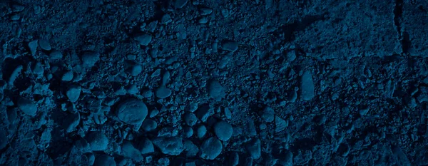 Abstract navy blue background. Dark blue grunge background. The combination of blue color and rough stone texture. Old damaged crumbling concrete surface. Toned concrete texture.