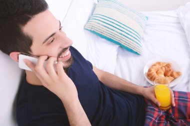 Yatakta telefonda konuşan adam.