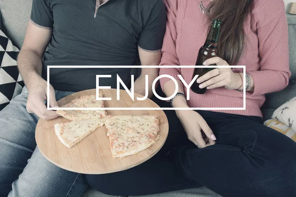 Молодая пара ест пиццу со знаком "Наслаждайтесь " — стоковое фото