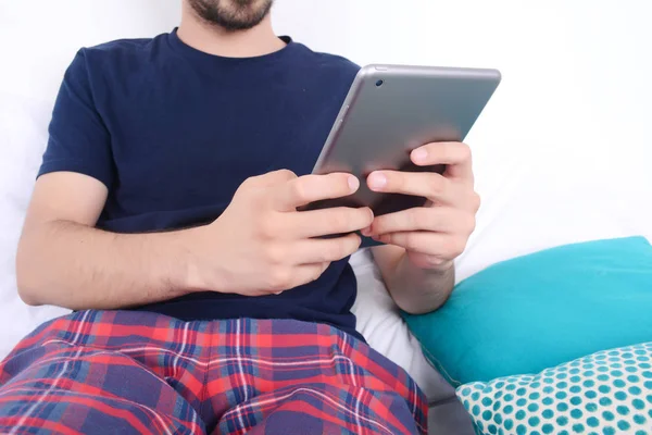 Ο άνθρωπος χρησιμοποιεί tablet στο κρεβάτι. — Φωτογραφία Αρχείου