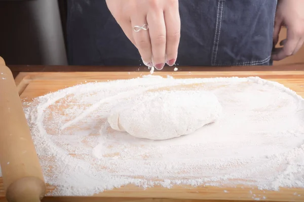 Женская рука добавляет муку в тесто . — стоковое фото