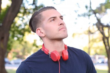 Genç adam bir parkta kulaklıklarla.