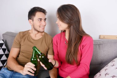 Çift kanepede bira içmek.