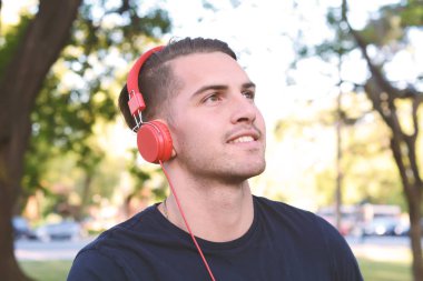 Genç adam bir parkta kulaklıklarla.