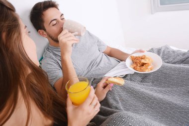 Çift yatakta kahvaltı yapıyor..