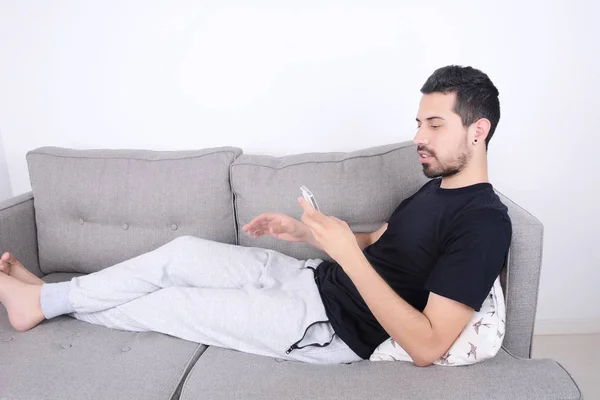 Hombre usando teléfono inteligente en el sofá . — Foto de Stock