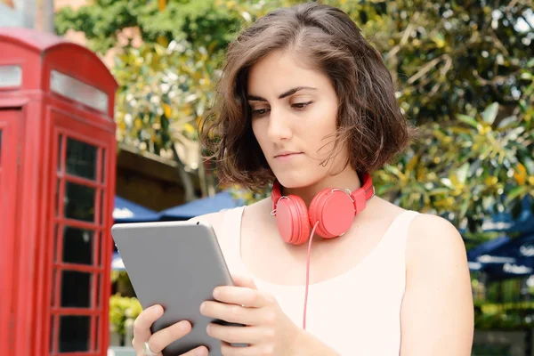 Frau mit roten Kopfhörern und Tablet. — Stockfoto