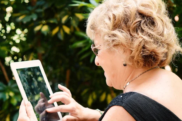 Elderly woman using tablet.