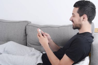 Kanepeye Smartphone kullanan adam.