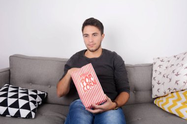 Patlamış mısır yemek ve film izlerken bir adam.