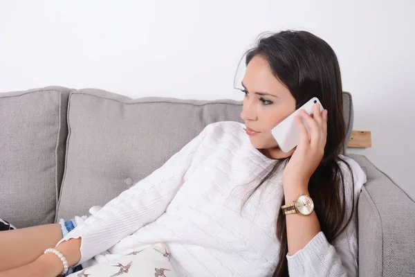Женщина разговаривает по телефону на диване . — стоковое фото