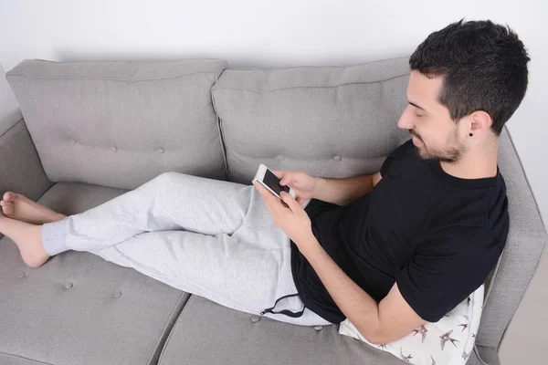 Hombre usando teléfono inteligente en el sofá . —  Fotos de Stock