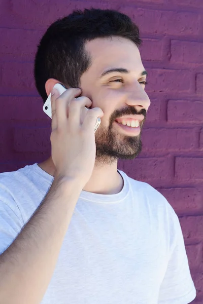 Beszél a telefonon ellen téglafal latin fiatalember portréja. A szabadban. — Stock Fotó