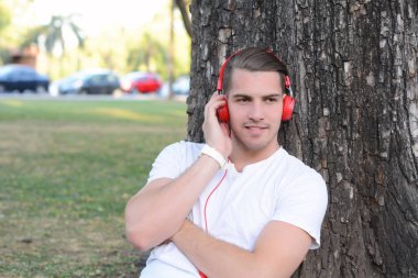 Genç adam bir parkta kulaklıklarla.