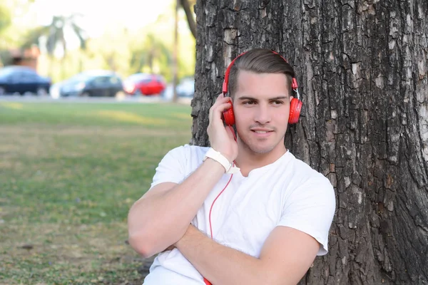 Genç adam bir parkta kulaklıklarla.