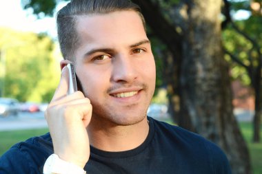 Young man talking on the phone. Outdoors. clipart