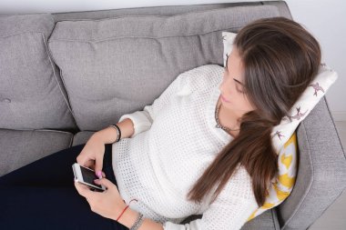 Kanepede akıllı telefon kullanan kadın..