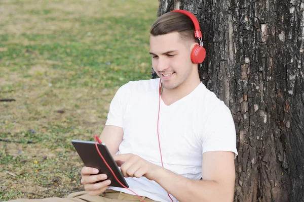 Giovane con le cuffie, in possesso di un tablet . — Foto Stock