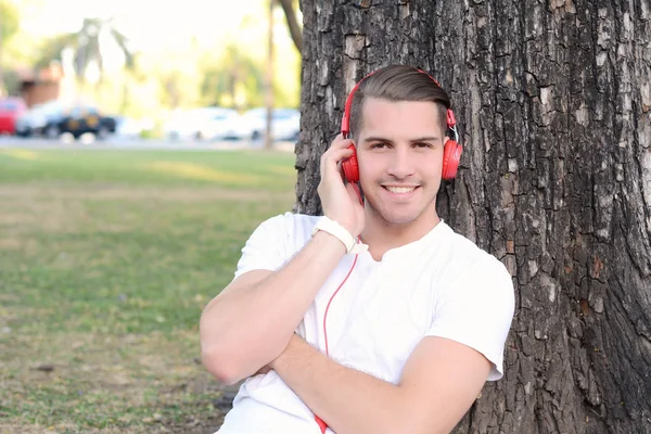 Giovane con le cuffie in un parco . — Foto Stock