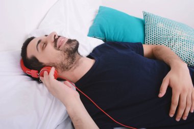 Adam yatakta müzik dinlemek.