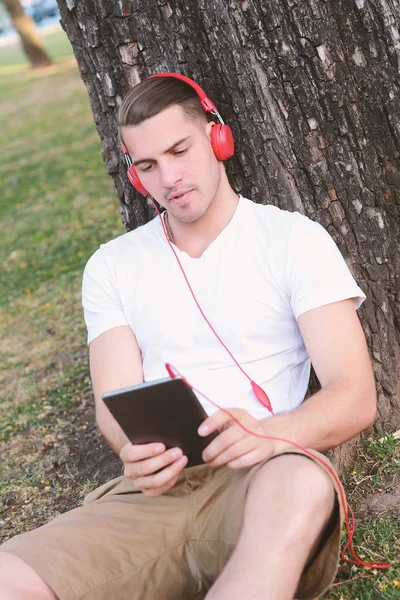 A fiatalember fejhallgató, gazdaság egy tabletta. — Stock Fotó