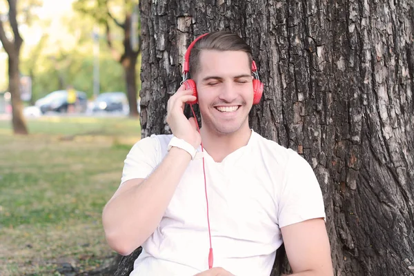 Giovane con le cuffie in un parco . — Foto Stock