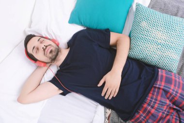 Adam yatakta müzik dinlemek.