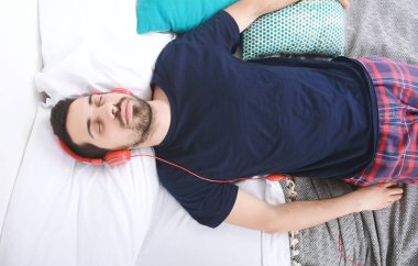 Adam yatakta müzik dinlemek.