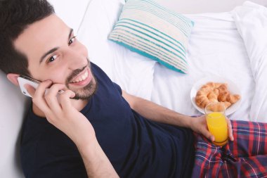 Yatakta telefonda konuşan adam.