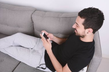 Kanepeye Smartphone kullanan adam.