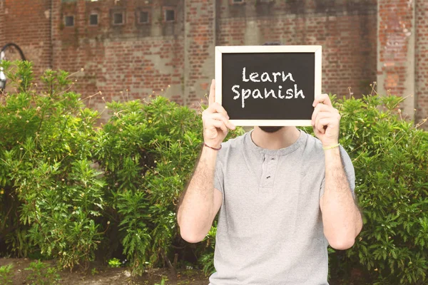 Man met bord met de tekst "Leer Spaans" — Stockfoto