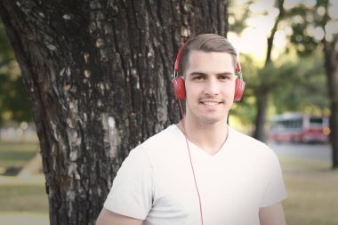 Genç adam bir parkta kulaklıklarla.