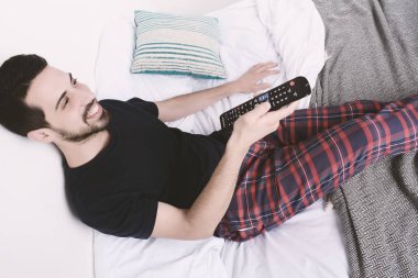 Adam yatakta TV izlerken.