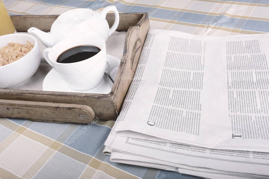 Breakfast tray with a newspaper, coffee and cereals.