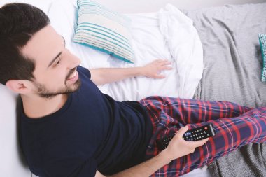 Adam yatakta TV izlerken.