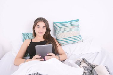 Yatağa tablet kullanan kadın.