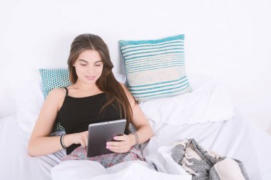 Yatağa tablet kullanan kadın.
