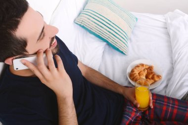 Yatakta telefonda konuşan adam.