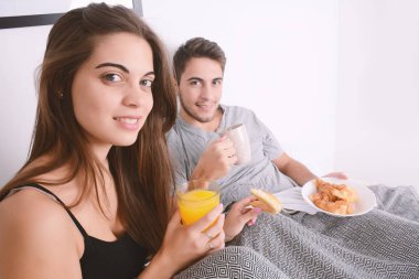 Çift yatakta kahvaltı yapıyor..