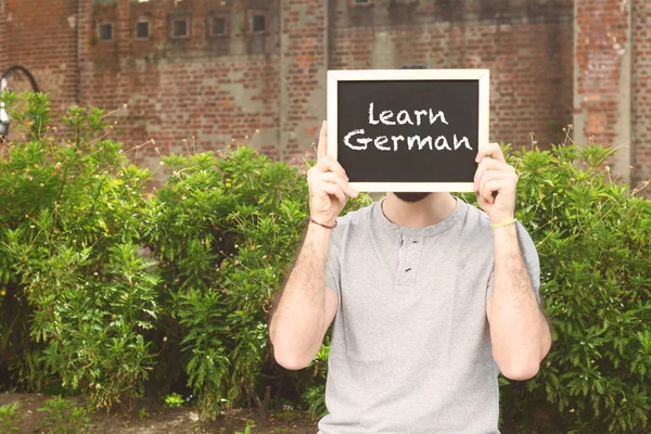 Man met bord met de tekst "Duits leren". — Stockfoto