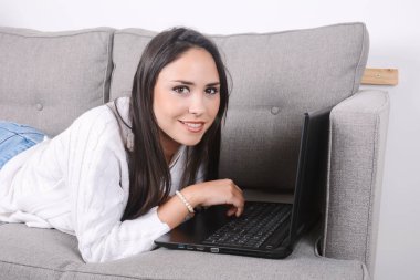 Kanepede dizüstü bilgisayar kullanan kadın.