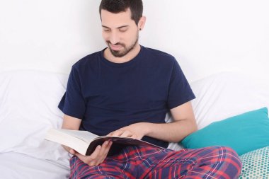 adam yatakta kitap okuma.