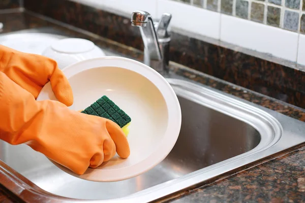 Manos en guantes de goma lavando platos con spon —  Fotos de Stock