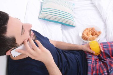 Yatakta telefonda konuşan adam.