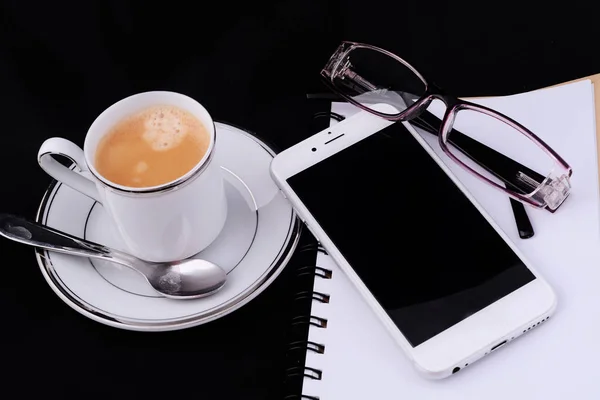 Uma xícara de café com um notepad e smartphone . — Fotografia de Stock